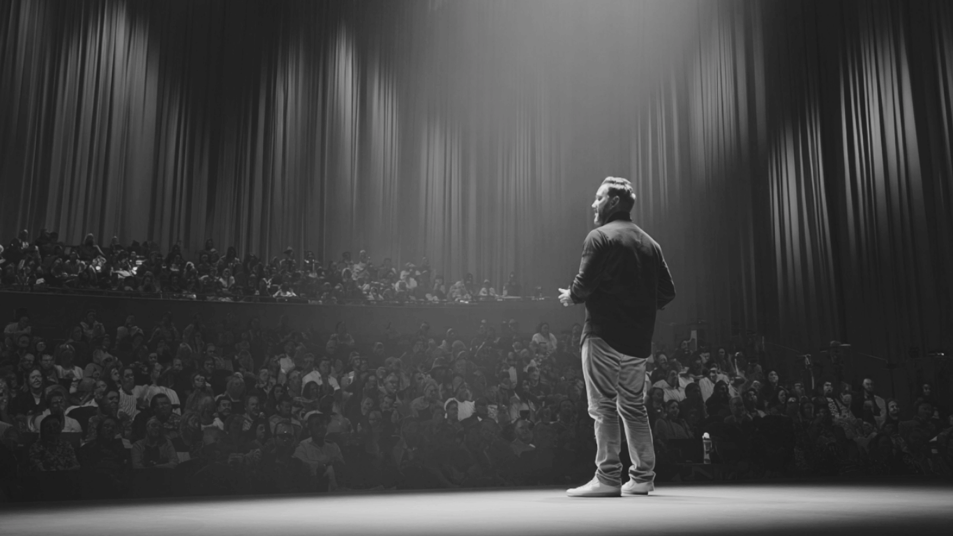 grayscale-professional-photo-of-jon-oliff-on-stage-at-a-conference-left